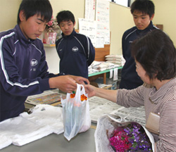 袋に詰めた花苗を渡す生徒（一宮支店）