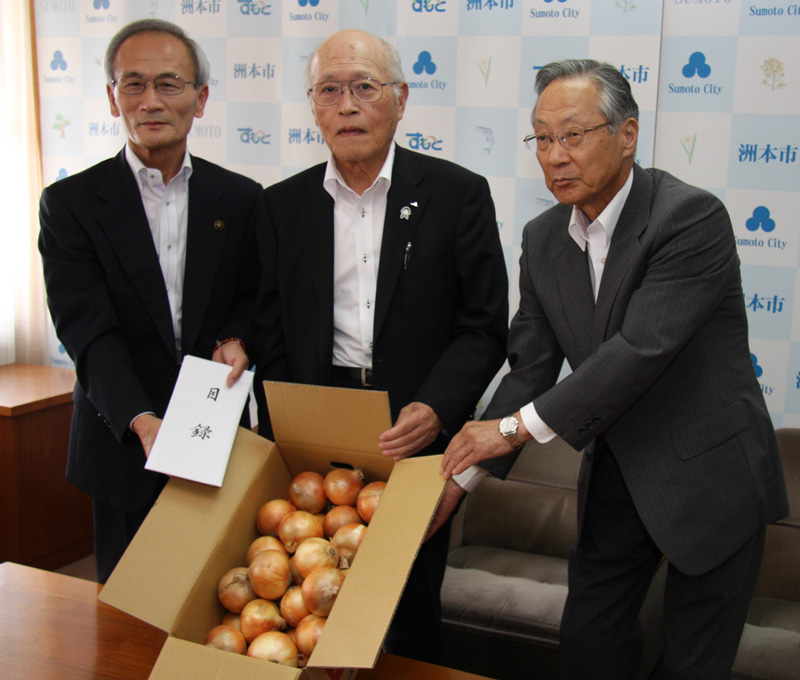 2015年6月のトピックス「「淡路島たまねぎ」を贈る石田正組合長(中央)と受け取る竹内通弘洲本市長(左)」